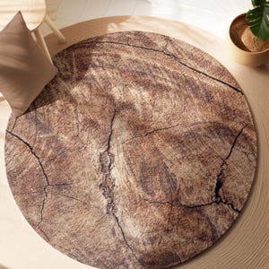 May include: A round, brown and beige area rug with a wood grain pattern and a cracked, weathered look.