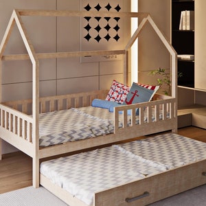 Puede incluir: Una cama de madera con forma de casa con un colchón estampado en blanco y gris y una cama auxiliar extraíble. La cama está en una habitación de color claro con un armario y una lámpara de pie.