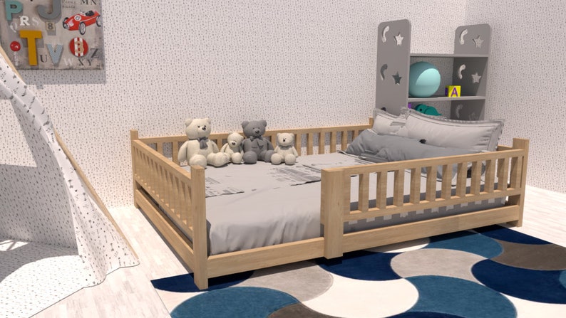May include: A wooden toddler bed with a grey mattress and a grey and white patterned sheet. Four teddy bears are sitting on the bed. The bed has a wooden railing around it. The bed is in a room with a white wall and a blue and grey rug.