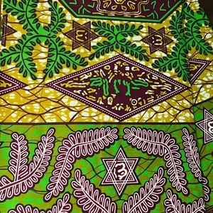 Peut inclure: Tissu vert et marron avec un motif r&eacute;p&eacute;titif de feuilles, d'&eacute;toiles et de formes g&eacute;om&eacute;triques. Le tissu a un design africain traditionnel.
