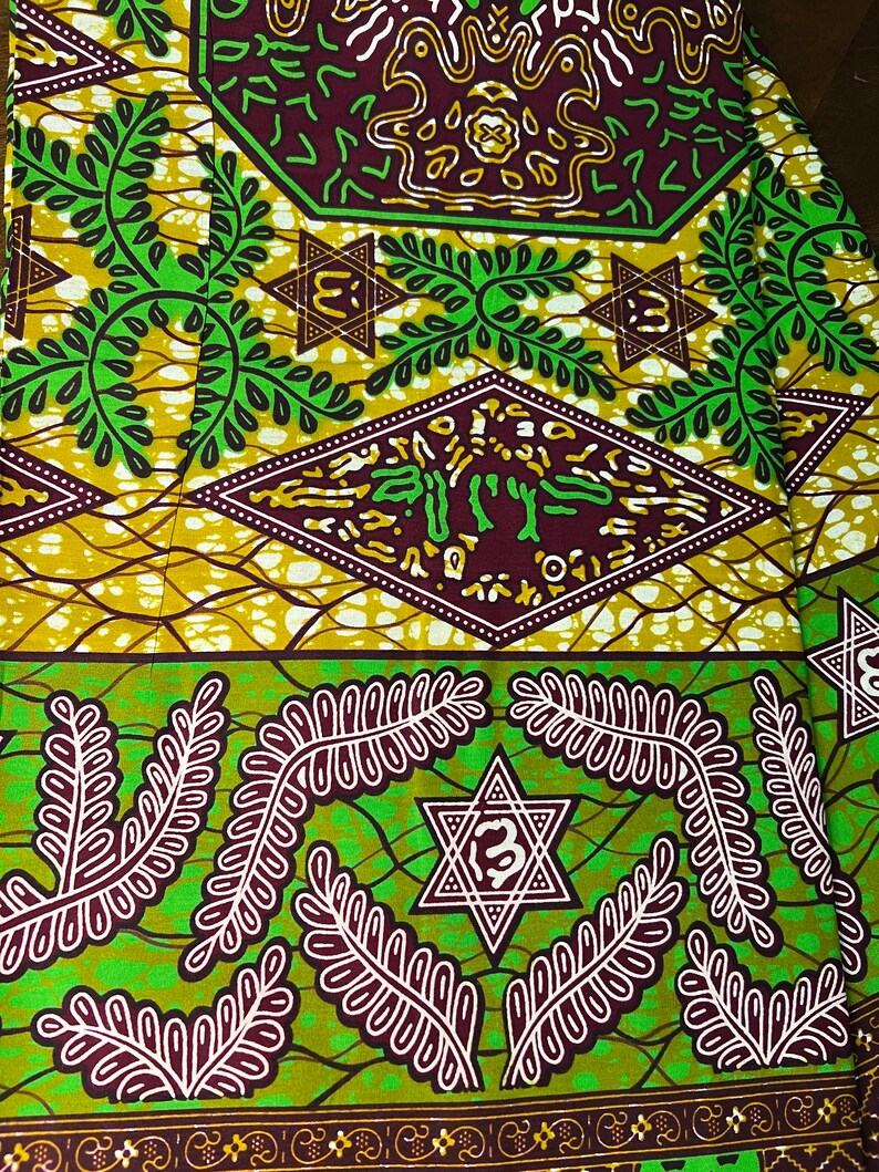Peut inclure: Tissu vert et marron avec un motif r&eacute;p&eacute;titif de feuilles, d'&eacute;toiles et de formes g&eacute;om&eacute;triques. Le tissu a un design africain traditionnel.