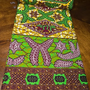 Peut inclure: Tissu vert et marron avec un motif g&eacute;om&eacute;trique compos&eacute; d'&eacute;toiles, de feuilles et d'un motif r&eacute;p&eacute;titif. Le tissu a une bordure blanche et une &eacute;tiquette qui indique "14/6216".