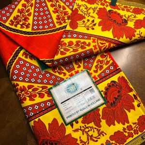 Puede incluir: Una tela amarilla y roja con un patr&oacute;n floral. La tela est&aacute; impresa con el texto "PRINTED BY VLISCO IN HOLLAND" y "VERITABLE WAX HOLLANDAIS".