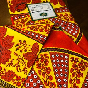 Puede incluir: Dos piezas de tela amarilla con un patr&oacute;n floral rojo y negro. La tela est&aacute; impresa con el texto "Impreso por Visco en Holanda" y "Garant&iacute;a."