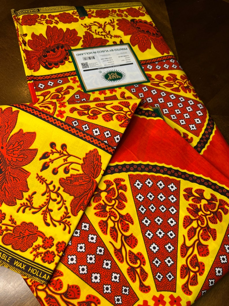Puede incluir: Dos piezas de tela amarilla con un patr&oacute;n floral rojo y negro. La tela est&aacute; impresa con el texto "Impreso por Visco en Holanda" y "Garant&iacute;a."