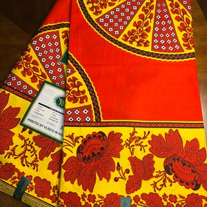 Puede incluir: Dos piezas de tela roja y amarilla con un patr&oacute;n floral. La tela est&aacute; impresa con un dise&ntilde;o geom&eacute;trico en blanco y negro y el texto "PRINTED BY VLISCO IN HOLLAND".