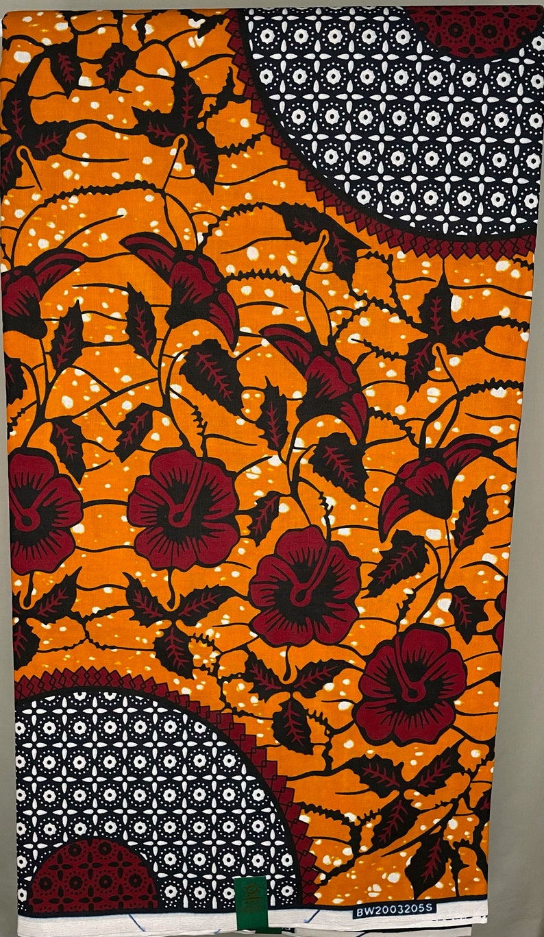 May include: Orange and white fabric with a repeating pattern of red flowers and black leaves. The fabric has a geometric pattern in the corners.