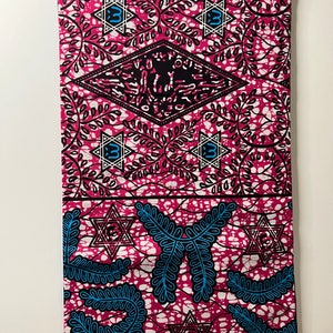 Op de afbeelding: Een levendige stof met een herhalend patroon van roze, zwart, wit en blauw. Het ontwerp omvat gestileerde sterren, ruitvormen en bladeren. Het kleurenpalet van de stof wordt gedomineerd door roze en zwart, met accenten van wit en blauw.