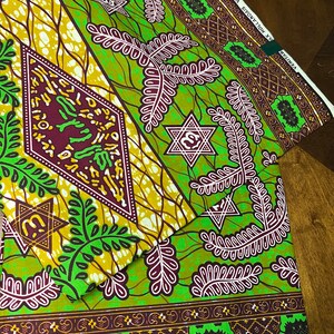 Peut inclure: Tissu vert et marron avec un motif r&eacute;p&eacute;titif de feuilles, d'&eacute;toiles et de diamants. Le tissu porte une &eacute;tiquette indiquant "VERITAS" et "MAX HOLLANDS - VLSO".