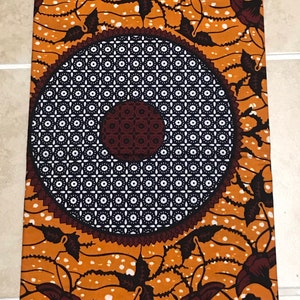 May include: Orange fabric with a white and black circular pattern and brown floral designs.