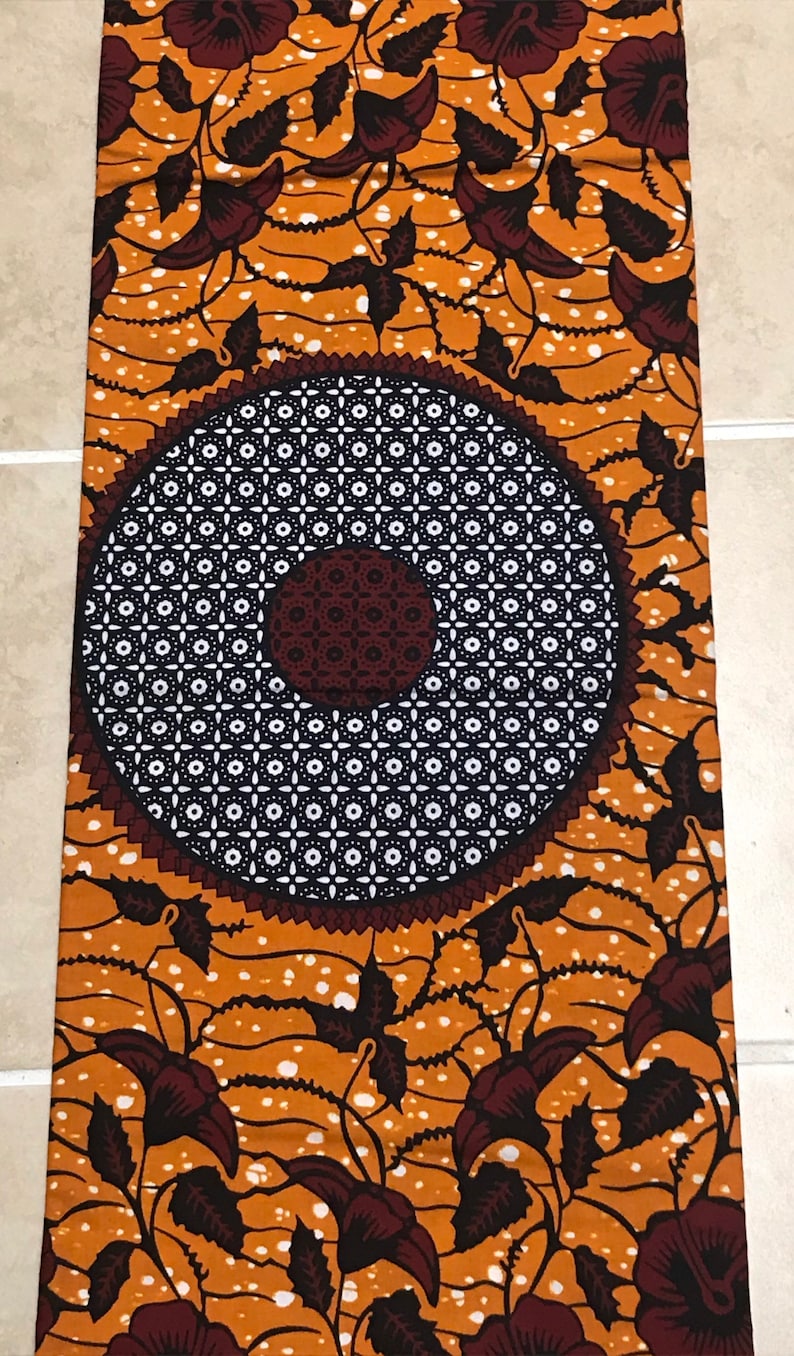 May include: Orange fabric with a white and black circular pattern and brown floral designs.