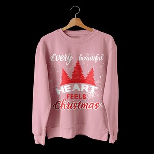 May include: Pink sweatshirt with a white graphic that says "Every beautiful heart feels Christmas" with a red heart and stylized trees.