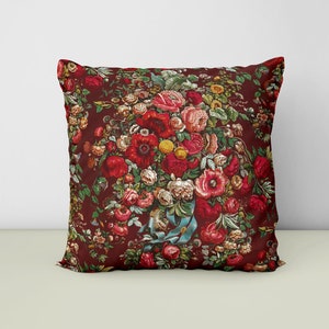 May include: A red pillow with a floral pattern featuring a bouquet of red, pink, and white flowers on a dark red background.