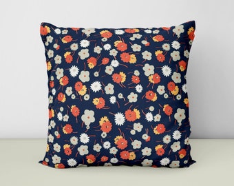 May include: A navy blue throw pillow with a floral pattern featuring red, orange, and white flowers.