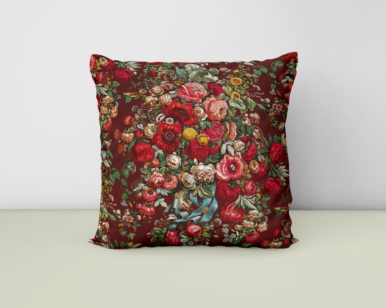 May include: A red pillow with a floral pattern featuring a bouquet of red, pink, and white flowers on a dark red background.