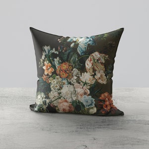 Op de afbeelding: Een donkergroen kussen met een bloemenprint met verschillende kleurrijke bloemen, waaronder roze, rode, blauwe en witte.