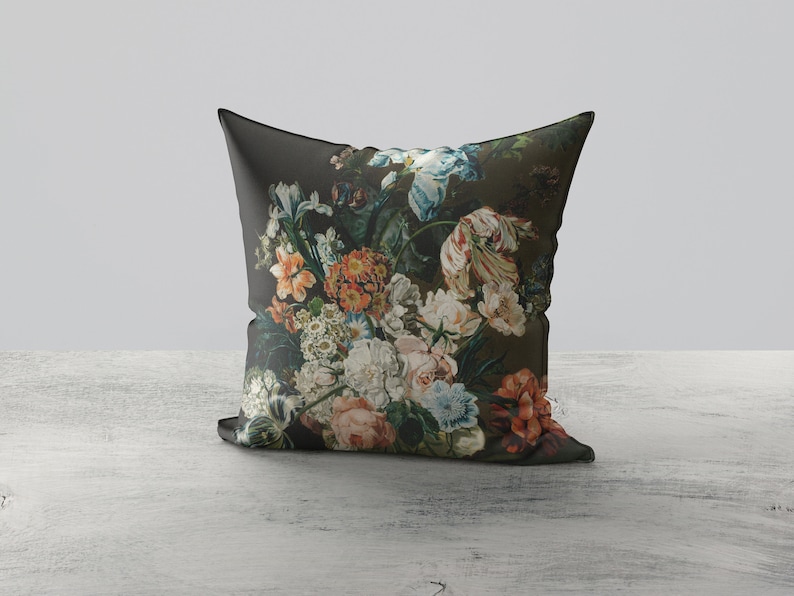 Op de afbeelding: Een donkergroen kussen met een bloemenprint met verschillende kleurrijke bloemen, waaronder roze, rode, blauwe en witte.