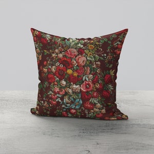 May include: A decorative pillow with a floral pattern featuring red, pink, and yellow flowers on a dark red background.