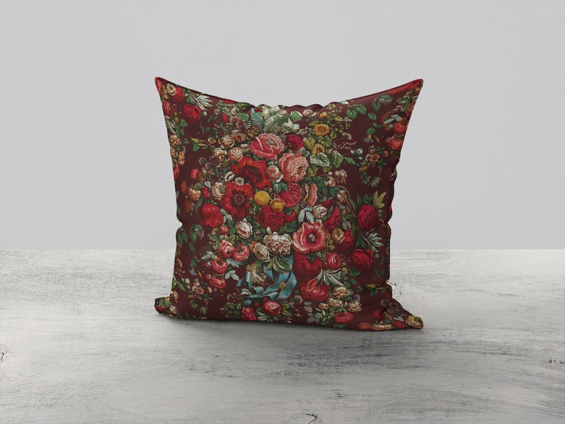 May include: A decorative pillow with a floral pattern featuring red, pink, and yellow flowers on a dark red background.
