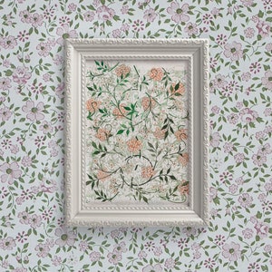 May include: A white framed print with a floral design in shades of green, orange, and white. The print is set against a background of a floral wallpaper with pink and green flowers.