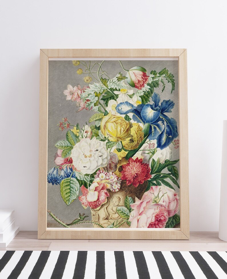 Op de afbeelding: Een ingelijste bloemenprint met een levendig boeket bloemen in een decoratieve vaas. Het kunstwerk toont een verscheidenheid aan bloemen in tinten geel, wit, rood, roze en blauw, tegen een grijze achtergrond. De lijst is van lichtgekleurd hout.