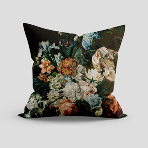 Op de afbeelding: Een zwart kussen met een bloemenprint met een verscheidenheid aan kleurrijke bloemen, waaronder rood, oranje, geel, wit, blauw en groen.