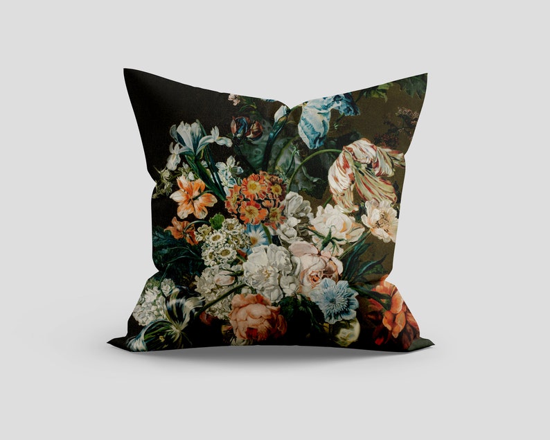 Op de afbeelding: Een zwart kussen met een bloemenprint met een verscheidenheid aan kleurrijke bloemen, waaronder rood, oranje, geel, wit, blauw en groen.