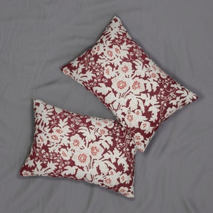 May include: Two rectangular throw pillows with a floral pattern. The pillows feature a burgundy background with a white and red floral design. The pillows are placed on a gray surface.