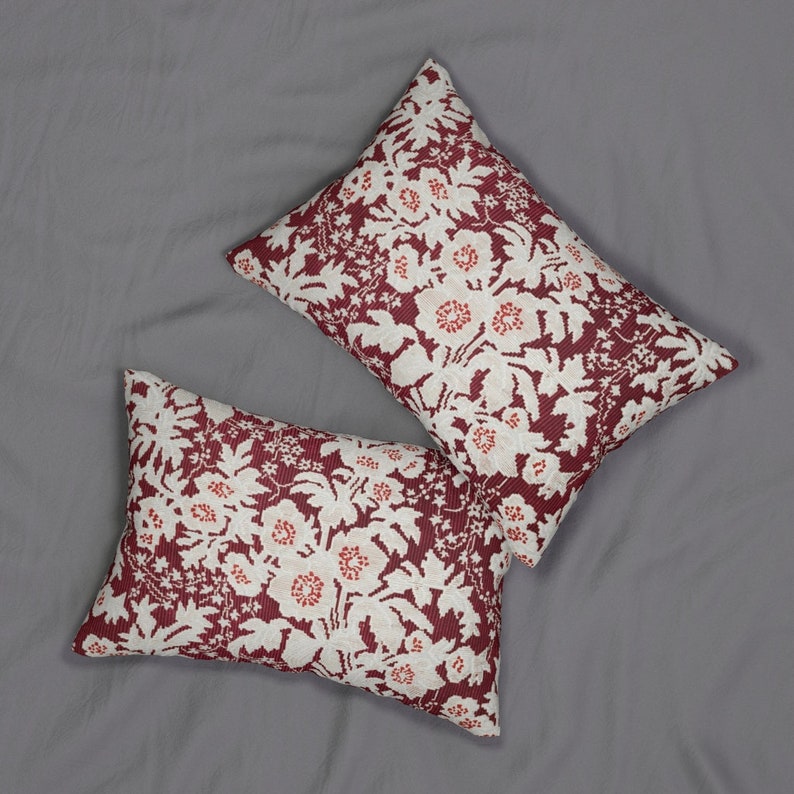 May include: Two rectangular throw pillows with a floral pattern. The pillows feature a burgundy background with a white and red floral design. The pillows are placed on a gray surface.