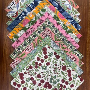 Puede incluir: Una colecci&oacute;n de servilletas de tela estampadas y coloridas. Cada servilleta presenta un dise&ntilde;o floral o bot&aacute;nico &uacute;nico en tonos de rosa, verde, azul, naranja y blanco. Las servilletas est&aacute;n dispuestas sobre una superficie de madera.