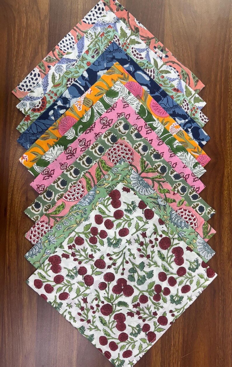 Puede incluir: Una colecci&oacute;n de servilletas de tela estampadas y coloridas. Cada servilleta presenta un dise&ntilde;o floral o bot&aacute;nico &uacute;nico en tonos de rosa, verde, azul, naranja y blanco. Las servilletas est&aacute;n dispuestas sobre una superficie de madera.