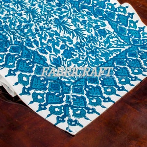 May include: A white textile with a teal floral pattern and the word "FABRICRAFT" printed across the center. The design features stylized flowers and leaves, with a darker teal border.