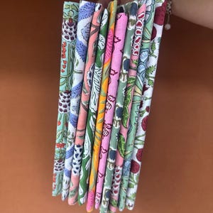 Puede incluir: Una pila de cuadrados de tela coloridos con estampados florales y bot&aacute;nicos. Las telas presentan una variedad de colores, incluyendo rosa, verde, azul y naranja. Las telas se mantienen juntas, mostrando los diferentes dise&ntilde;os.
