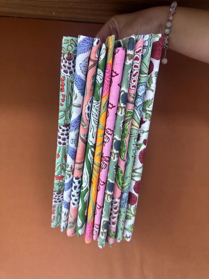 Puede incluir: Una pila de cuadrados de tela coloridos con estampados florales y bot&aacute;nicos. Las telas presentan una variedad de colores, incluyendo rosa, verde, azul y naranja. Las telas se mantienen juntas, mostrando los diferentes dise&ntilde;os.