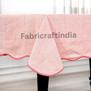 May include: A rectangular tablecloth with a red and white striped pattern. The tablecloth has a scalloped edge with a red trim. The text "Fabriccraftindia" is printed on the tablecloth.