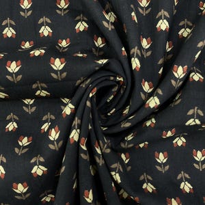 May include: Close-up of a dark fabric with a repeating floral pattern. The flowers are in shades of cream, brown, and red, set against a black background. The fabric is gathered, showing the texture and folds of the material.