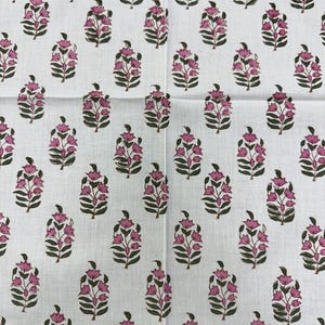 May include: White fabric with a repeating pattern of pink floral bouquets and green leaves. The fabric has a scalloped edge in a light green color. The floral design is a block print style.