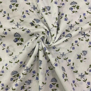 May include: White fabric with a floral pattern of small blue flowers and green leaves on winding vines. The fabric is gathered, showing soft folds and shadows. The design creates a delicate and intricate pattern across the material.