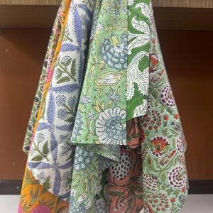Puede incluir: Una colecci&oacute;n de servilletas de tela estampadas y coloridas. Las servilletas presentan dise&ntilde;os florales y bot&aacute;nicos en tonos verdes, azules, naranjas y rosas. La tela parece ser de algod&oacute;n o un material similar, con un aspecto ligeramente texturizado.