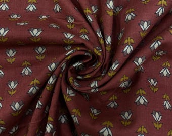 May include: Close-up of a burgundy fabric with a repeating floral pattern. The design features white and gray flowers with yellow-green leaves. The fabric is folded, creating shadows and texture.