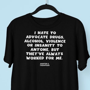 Puede incluir: Camiseta negra con texto blanco que dice "Odio defender las drogas, el alcohol, la violencia o la locura a nadie, pero siempre me ha funcionado." El texto se atribuye a Hunter S. Thompson.