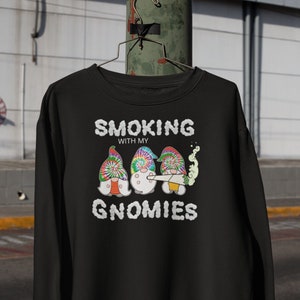 May include: Black sweatshirt with a graphic of three gnomes wearing tie-dye hats and smoking a joint. The text "SMOKING WITH MY GNOMIES" is printed below the gnomes.