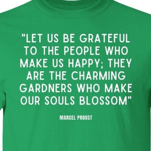 May include: Green t-shirt with a white quote by Marcel Proust: "Let us be grateful to the people who make us happy; they are the charming gardeners who make our souls blossom."