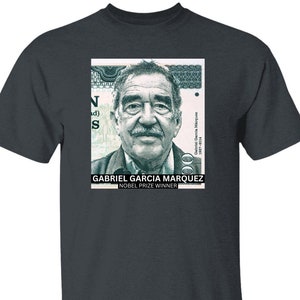 以下が含まれることがあります： ガブリエル・ガルシア・マルケス、コロンビアの小説家、短編作家、脚本家、ジャーナリストのグラフィックがプリントされたダークヘザーグレーのTシャツ。グラフィックは、「ガブリエル・ガルシア・マルケス」と「ノーベル賞受賞者」の文字が書かれた切手です。