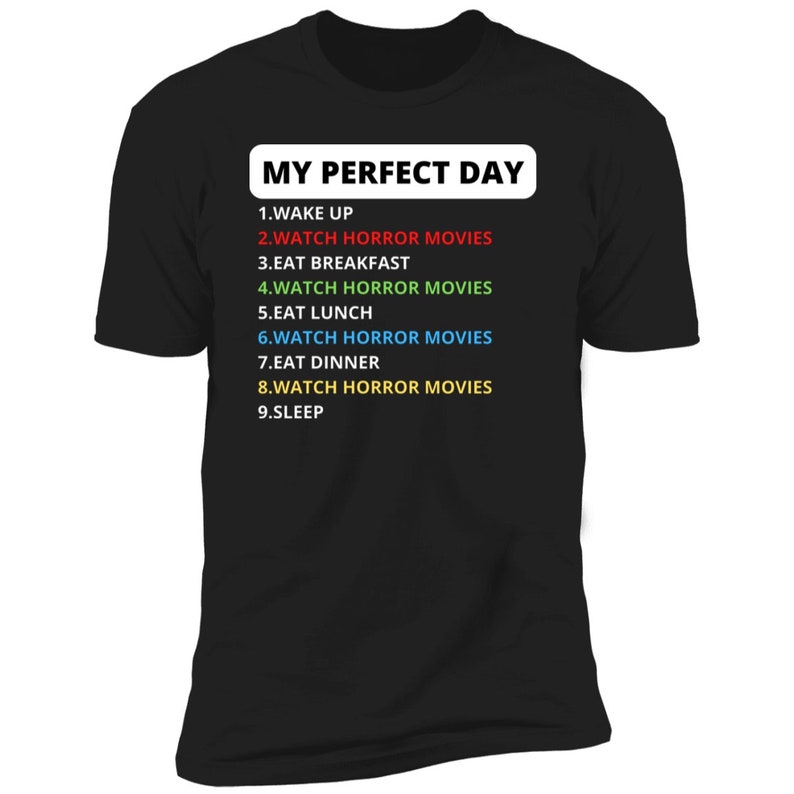 May include: Black t-shirt with white text that reads "MY PERFECT DAY" and a list of activities, including "WATCH HORROR MOVIES" in different colours.