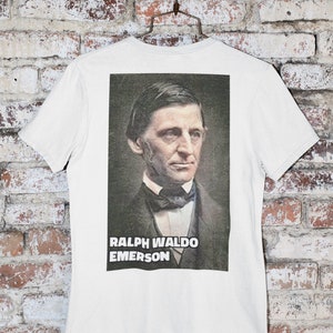 Puede incluir: Camiseta blanca con una imagen en blanco y negro de Ralph Waldo Emerson en la parte posterior. La imagen est&aacute; en un marco rectangular con el texto "Ralph Waldo Emerson" debajo.