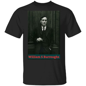May include: Black and white photo of William S. Burroughs, an American novelist, essayist, and Beat Generation writer. He is wearing a suit and tie and is standing in front of a wooden door. The text "William S. Burroughs" is printed below the photo.