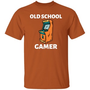 K&ouml;nnte beinhalten: Orangefarbenes T-Shirt mit wei&szlig;em Text "Old School Gamer" und einem Cartoon-Bild eines Arcade-Spiels.
