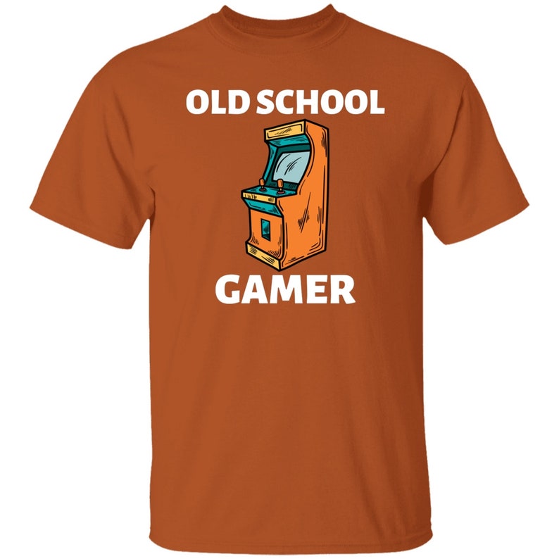 K&ouml;nnte beinhalten: Orangefarbenes T-Shirt mit wei&szlig;em Text "Old School Gamer" und einem Cartoon-Bild eines Arcade-Spiels.