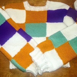 May include: A colourful knitted jumper with a checkered pattern in white, orange, purple, and green.